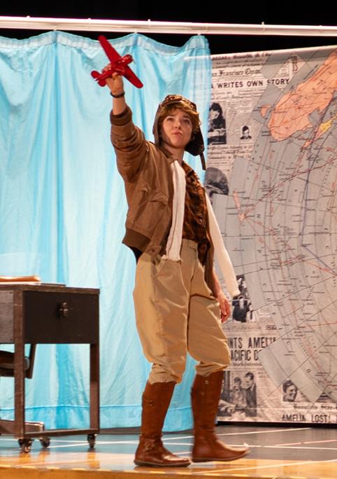 Amelia Earhart holds model plane in play performance